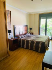 sypialnia z dużym łóżkiem i balkonem w obiekcie Hotel AV Apartamentos Lobios w mieście Lobios