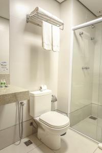 a white bathroom with a toilet and a shower at Dubai Suites in Montes Claros