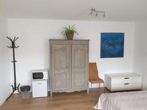 a bedroom with a large wooden cabinet with a plant on top at MAISON DES FLEURS in Brussels