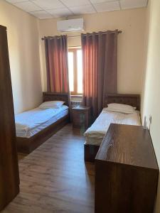 a room with two beds and a table and a window at Uzumfermer Hotel & Winery in Tashkent
