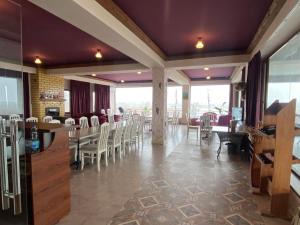 a restaurant with white chairs and tables and windows at Uzumfermer Hotel & Winery in Tashkent