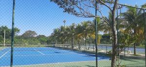 a tennis court with palm trees and a fence at Loft Sahy - Condado Aldeia dos Reis in Mangaratiba +29 photos