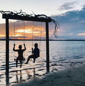 a group of people sitting on a swing on the beach at Ocean Tally in Upper Bogue