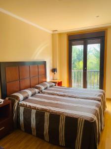 sypialnia z dwoma łóżkami i dużym oknem w obiekcie Hotel AV Apartamentos Lobios w mieście Lobios