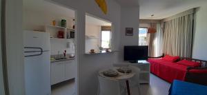 een kleine woonkamer met een rode bank en een keuken bij Loft Sahy - Condado Aldeia dos Reis in Mangaratiba