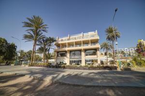 um grande edifício branco com palmeiras em frente em Sea view hotel em Aqaba