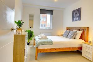 a bedroom with a bed with a wooden frame and a window at Modern & Stylish 2BR Apartment - Queens House in Coventry