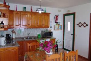 a kitchen with wooden cabinets and a table with flowers at Apartamentos Finca Casa Jardín in Tijarafe
