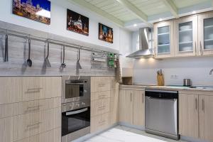 una cucina con armadietti in legno ed elettrodomestici in acciaio inossidabile di 2Bedroom Duplex in Hortaleza Near Metro a Madrid