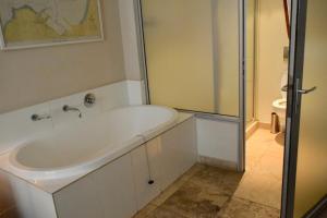 a white bath tub in a bathroom with a shower at Stylish Apartment with Rooftop Pool and City Views in Cape Town