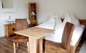 a bedroom with a bed with a wooden table and a sink at Untermühlbauer Fam. Schreder in Saalfelden am Steinernen Meer