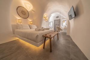 a bedroom with a bed and a table and a tv at Eternity Suites Santorini in Fira