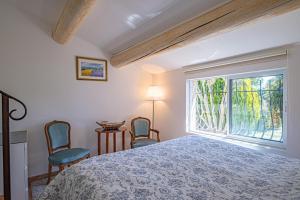 a bedroom with a bed and two chairs and a window at La Roubine, Velleron in Velleron