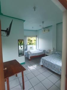 Cette chambre comprend 2 lits, une table et un miroir. dans l'établissement Hotel Gamito, à Puerto Escondido