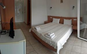 a bedroom with a bed with white sheets and a mirror at Plataria Palace in Plataria