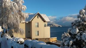 una casa ricoperta di neve accanto a un corpo d'acqua di Lago apARTments a San Carlos de Bariloche