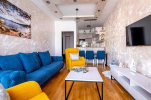 a living room with a blue couch and yellow chairs at S&S Apartment Becici in Budva
