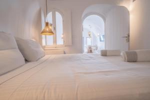 a white bedroom with a large white bed with two windows at Eternity Suites Santorini in Fira +121 photos