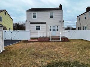 Uma casa branca com uma cerca branca à frente. em Governors Villa Long Island em Hempstead