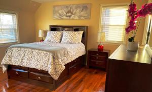 a bedroom with a bed and two dressers and two windows at Governors Villa Long Island in Hempstead