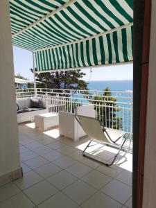 a balcony with a chair and an umbrella and the ocean at Casa sul mare in Acciaroli