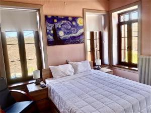 a bedroom with a bed and a painting on the wall at Helios - Epirus Traditional guesthouse in Dolianá