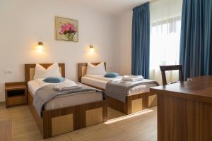 a hotel room with two beds and a desk at Pensiunea Transilvania in Sibiu