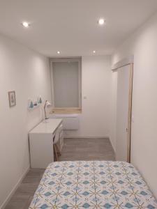 een witte slaapkamer met een bed en een wastafel bij LAN'ApparT in Morez