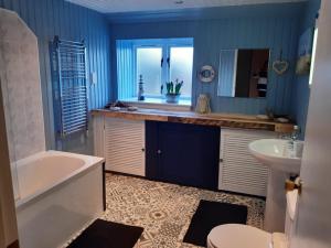 ein Badezimmer mit blauen Wänden, einer Badewanne und einem Waschbecken in der Unterkunft Craighlaw Arms Boutique B&B in Kirkcowan