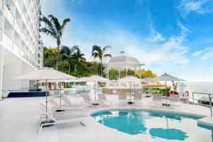 uma piscina com cadeiras e guarda-sóis num edifício em Grand Park Royal Puerto Vallarta - All Inclusive em Puerto Vallarta