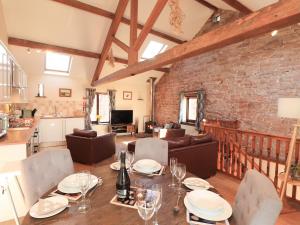 a dining room and living room with a brick wall at Stable Cottage in Wigton