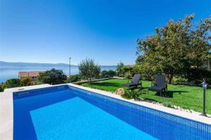 a swimming pool with two chairs and a view of the water at Apartment in Novi Vinodolski 15442 in Novi Vinodolski