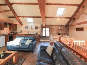 a living room with a leather couch and a table at Hayloft Cottage in Wigton