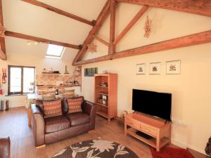 uma sala de estar com um sofá e uma televisão de ecrã plano em Horseshoe Cottage em Wigton