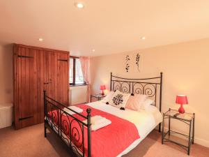 a bedroom with a large bed with a red bedspread at Horseshoe Cottage in Wigton