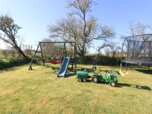 a playground with a toy tractor and a swing at Hayloft Cottage in Wigton