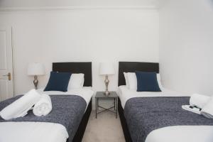 two beds in a hotel room with blue and white pillows at Spacious Apartments in Bath