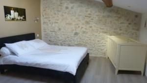 a bedroom with a bed and a stone wall at La Pause Ardéchoise in Saint-Remèze