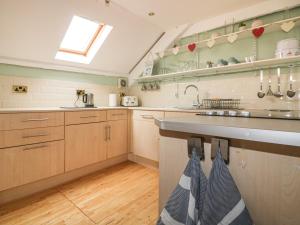 a large kitchen with wooden cabinets and a sink at The Blue House in Tintagel
