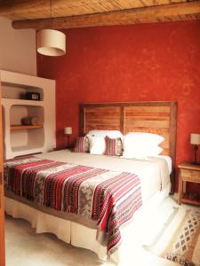 a bedroom with a large bed with a red wall at Tierra Quebrada Cabañas in Purmamarca