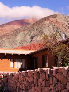 uma casa com uma parede de pedra ao lado de uma montanha em Tierra Quebrada Cabañas em Purmamarca