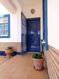uma porta azul num edifício com dois vasos de plantas em ONUBA golf, sea & sun em El Portil
