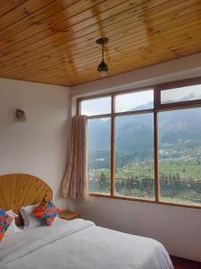 Un dormitorio con dos camas y una gran ventana. en Hotel BHRIGU, en Manali