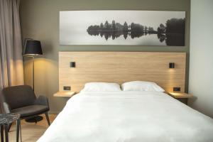 a bedroom with a large white bed and a chair at Park Inn by Radisson Vilnius Airport Hotel & Conference Centre in Vilnius