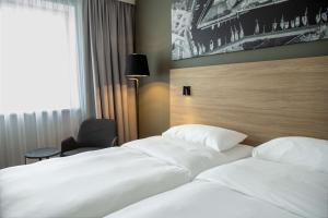 two white beds in a hotel room with a window at Park Inn by Radisson Vilnius Airport Hotel & Conference Centre in Vilnius
