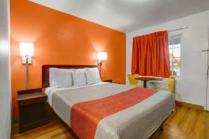 sypialnia z dużym łóżkiem z pomarańczową ścianą w obiekcie Motel 6-Marysville, CA w mieście Marysville