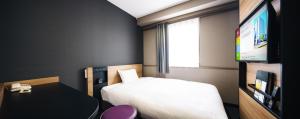 um pequeno quarto com uma cama e uma televisão em Hakata Nakasu Washington Hotel Plaza em Fukuoka