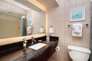a bathroom with a sink and a toilet and a mirror at Hotel Lulu, BW Premier Collection in Anaheim