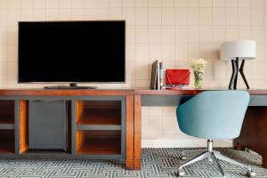 a desk with a television and a blue chair at Hotel Lulu, BW Premier Collection in Anaheim