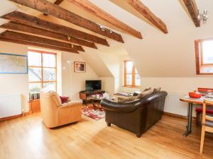 a living room with leather furniture and wooden ceilings at Larch Cottage in Weem